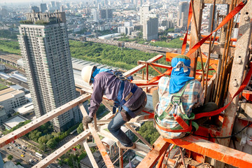 Construction worker wear standard personal protective equipment dismantle steel structure at height rise building project