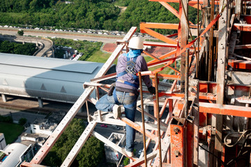 Construction worker wear standard personal protective equipment dismantle steel structure at height rise building project