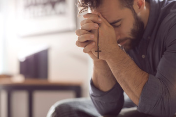 religious young man praying to god at home