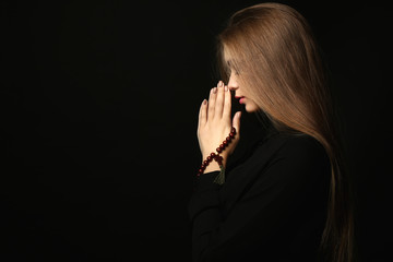 Wall Mural - Beautiful young woman praying on dark background