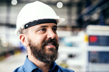 A portrait of an industrial man engineer with helmet in a factory.