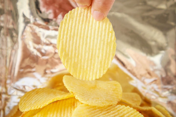 Hand hold potato chips inside snack foil bag