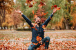 Young man throwing autumn leaves in the air