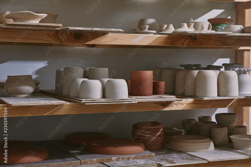 ceramic bowls and dishes on wooden shelves at pottery studio - obrazy, fototapety, plakaty 