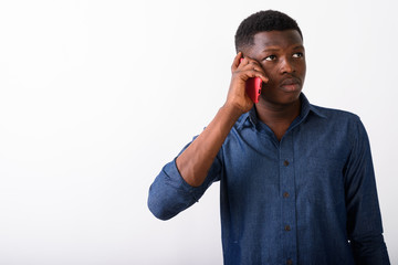 Wall Mural - Studio shot of young black African man thinking while talking on