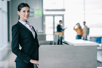 Wall Mural - beautiful young woman smiling at camera while working at check-in desk in airport