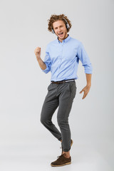 Wall Mural - Full length portrait of a cheerful young man with curly hair