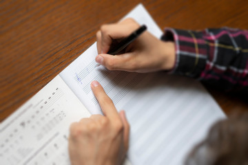 close up student hands write down music notes on class in school f