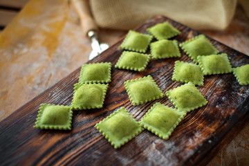 Wall Mural - colourful fresh ravioli with spinach on Board with flour. making pasta at home