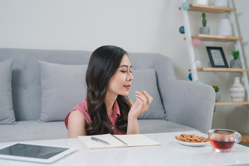 young asian woman thinking ideas while sitting at a stone desk in her apartment