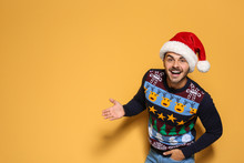 Young Man In Christmas Sweater And Hat On Color Background. Space For Text