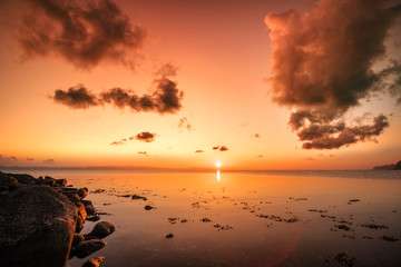 Wall Mural - sunrise over the sea by the shore with rocks