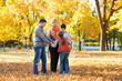 © soleg - Happy family walks in autumn city park. Children and parents posing, smiling, playing and having fun. Bright yellow trees.