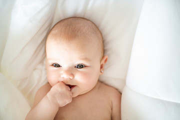 Wall Mural - A Cute baby girl on a white bed at home