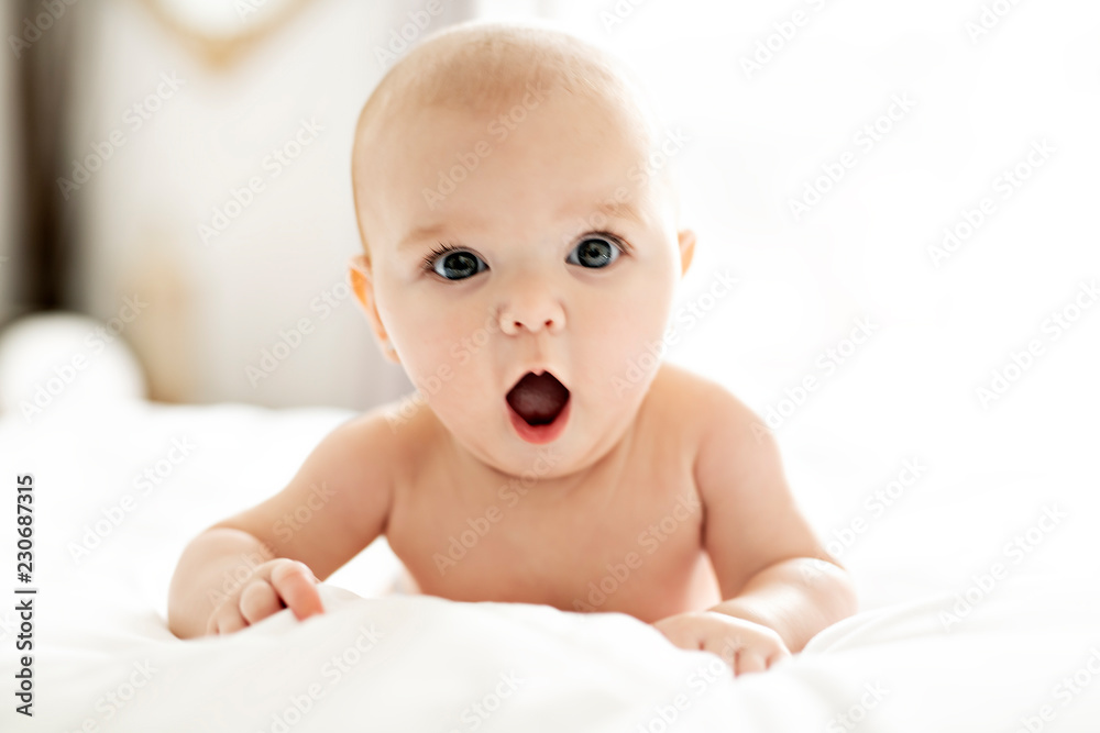 A Cute baby girl on a white bed at home yawn - obrazy, fototapety, plakaty 