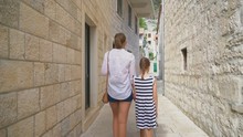 Mother With Her Daughter Walking In The Old Town.