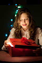 Beautiful girl opens a box with a gift