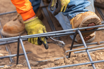 Wall Mural - Worker Securing Steel Rebar Framing With Wire Plier Cutter Tool At Construction Site