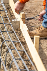 Wall Mural - Worker Securing Steel Rebar Framing With Wire Plier Cutter Tool At Construction Site