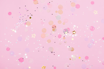 Pink pastel festive background with confetti and sparkles. Flat lay style.