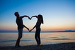 © el.rudakova - sunset silhouette of young couple in love holding hands at beach