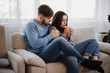 © Vadym - Young couple sitting at sofa with hot drinks. Love, relationships, conversation, winter weekend concept