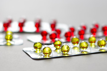 Transparent, yellow and red vitamin pills in blister packs on a light background