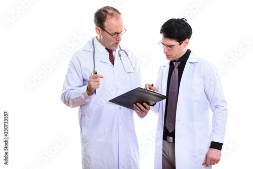 Fotografia Mature man doctor and young man doctor both writing on clipboard
