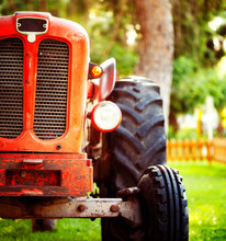 Croppped Photo Of Old Vintage Red Tractor Standing On A Farm Field At Sunset.