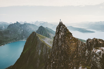 Man climber standing on cliff mountain edge above fjord in Norway travel adventure extreme lifestyle journey vacations solitude emotions mountains landscape