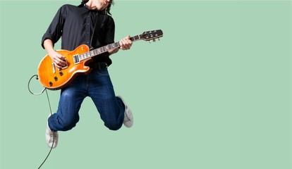 Male Guitarist playing music on grey wall