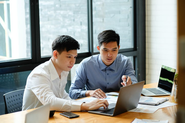 Two man business discussion with laptop computer and finance document paper.