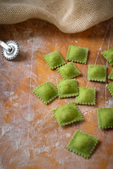 Wall Mural - uncooked homemade ravioli with flour on wooden background