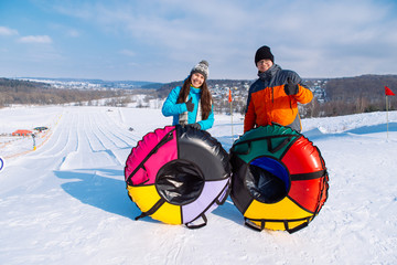 couple at top of the hill ready for snow tubing. winter activity. slide from the top