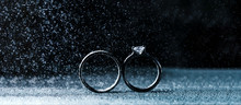 Two Wedding Rings In Infinity Sign With Sparkling Light Mist. Love Concept On Black Background. Wide Panoramic Horizontal View