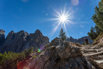 Trekkers along path in a sunny day, with amazing Dolomite peaks background South Tyrol, Italy