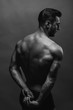© VAKSMANV - Bodybuilding. Strong man posing on background. Athletic young boy showing muscles.