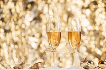 Two full champagne glasses with bokeh lights in the background