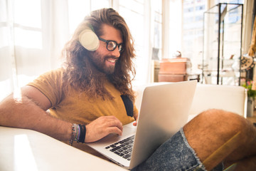 young man with long hair working with his laptop at home