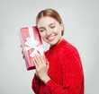 © artmim - Cheerful woman in red sweater holding gift box and having fun