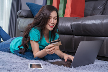 Sticker - happy woman using laptop computer for online shopping with credit card in living room