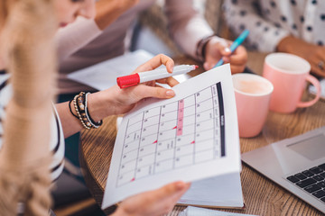 Wall Mural - Daily planning. Close up of a calendar being in female hands while planning the schedule