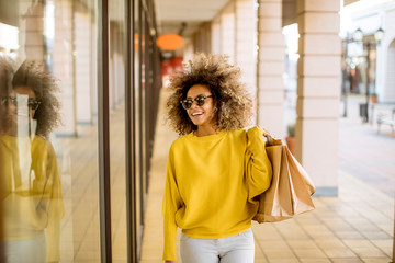 Wall Mural - Young black woman with curly hair in shopping