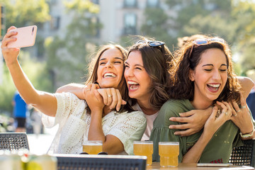 Euphoric girl friends taking selfie together on terrace.