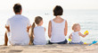 © JackF - back view on family of four sitting on beach .