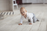 Fototapeta  - baby of 10 months is crawling wooden floor, real