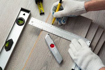 concept of home improvement. man measures the new laminate