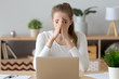 © fizkes - Frustrated sad millennial young woman sitting at the office desk or home. Covering face with hand female worker feels unhealthy headache or eyestrain. Student has a problems receive bad news concept