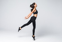 Full Length Of Jumping Fitness Woman Over Gray Background
