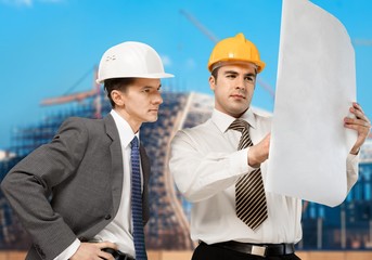 two engineers men at construction site watching blueprint